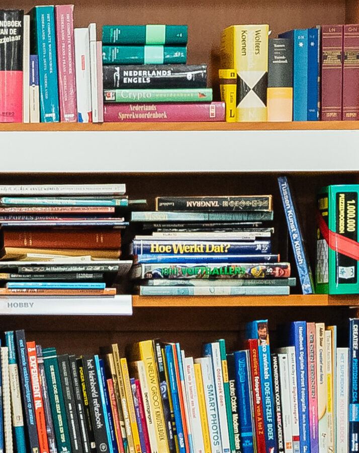 Boekenkast gevuld met diverse boeken over taal, wetenschap en hobby's in een bibliotheek of studeerkamer.